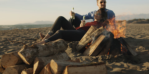 Image showing Loving Young Couple Sitting On The Beach beside Campfire drinkin