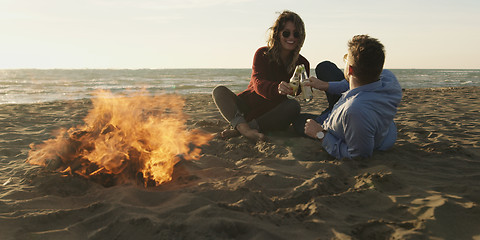 Image showing Loving Young Couple Sitting On The Beach beside Campfire drinkin