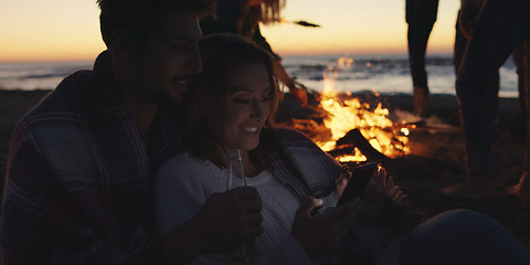 Image showing Couple enjoying bonfire with friends on beach