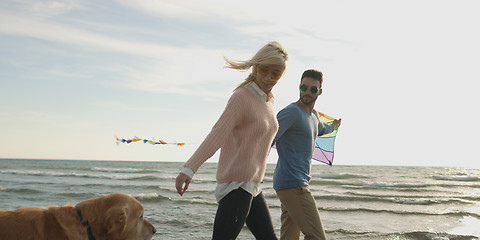 Image showing couple with dog having fun on beach on autmun day