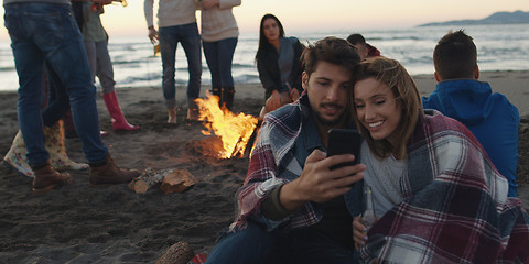 Image showing Couple enjoying bonfire with friends on beach