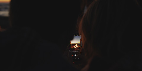 Image showing Couple taking photos beside campfire on beach