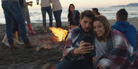 Image showing Couple enjoying bonfire with friends on beach