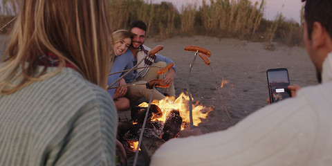 Image showing Group Of Young Friends Sitting By The Fire at beach