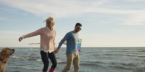 Image showing couple with dog having fun on beach on autmun day