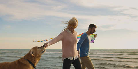 Image showing couple with dog having fun on beach on autmun day