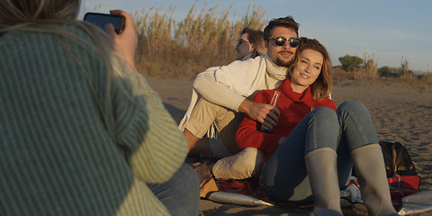 Image showing Loving Young Couple Sitting On The Beach beside Campfire drinkin