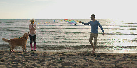 Image showing couple with dog having fun on beach on autmun day