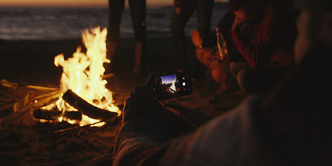 Image showing Couple taking photos beside campfire on beach