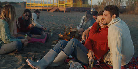 Image showing Loving Young Couple Sitting On The Beach beside Campfire drinkin