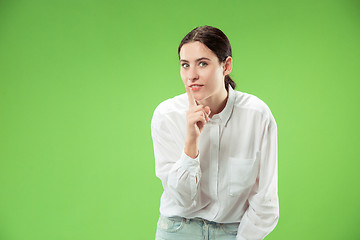 Image showing The young woman whispering a secret behind her hand over green background