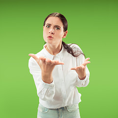 Image showing Beautiful female half-length portrait isolated on green studio backgroud. The young emotional surprised woman