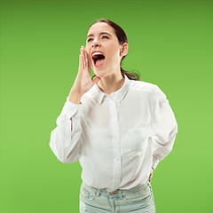 Image showing Isolated on green young casual woman shouting at studio