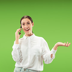 Image showing Young beautiful woman using mobile phone studio on green color background