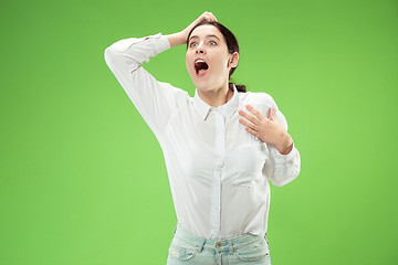 Image showing Beautiful woman looking suprised isolated on green