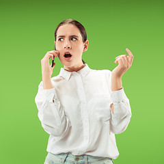 Image showing Young beautiful woman using mobile phone studio on green color background