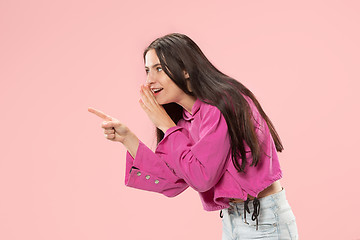 Image showing The young woman whispering a secret behind her hand over pink background