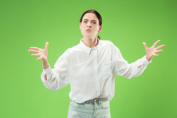 Image showing Portrait of an angry woman looking at camera isolated on a green background
