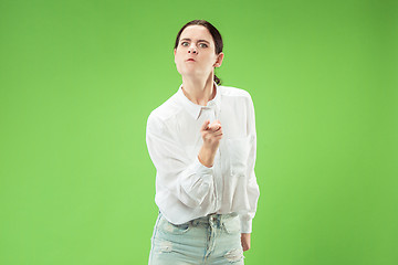 Image showing Portrait of an angry woman looking at camera isolated on a green background