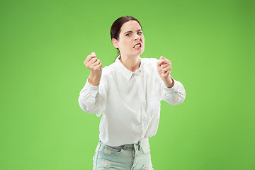 Image showing Portrait of an angry woman looking at camera isolated on a green background