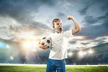 Image showing Young boy with soccer ball doing flying kick at stadium