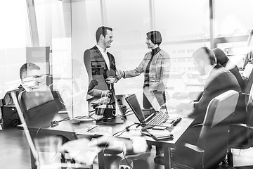 Image showing Confident business people shaking hands in moder corporate office.