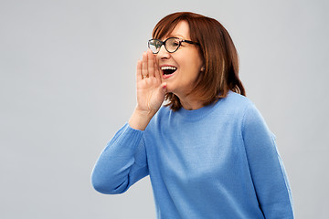 Image showing senior woman in glasses calling over grey