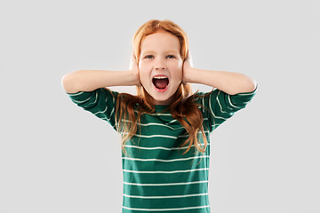 Image showing screaming red haired girl closing ears by hands