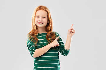 Image showing smiling red haired girl pointing fingers upwards