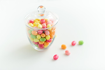 Image showing glass jar with candy drops over white background