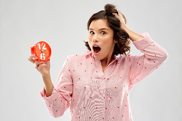 Image showing shocked young woman in pajama with alarm clock