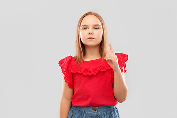 Image showing serious girl in red shirt pointing finger up