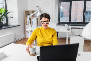 Image showing businesswoman with laptop drinks coffee at office