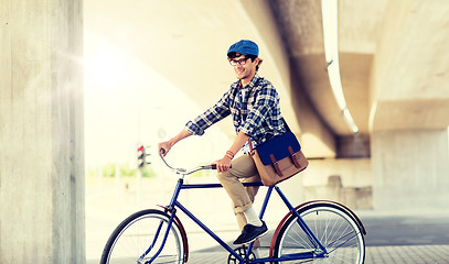 Image showing happy hipster man with bag riding fixed gear bike