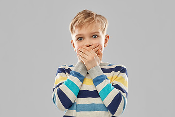 Image showing shocked little boy closing his mouth by hands