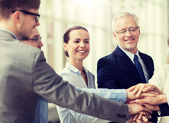 Image showing business people putting hands on top in office