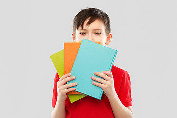 Image showing shy schoolboy hiding behind books