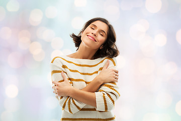 Image showing happy woman in striped pullover hugging herself