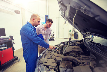 Image showing auto mechanic with clipboard and man at car shop