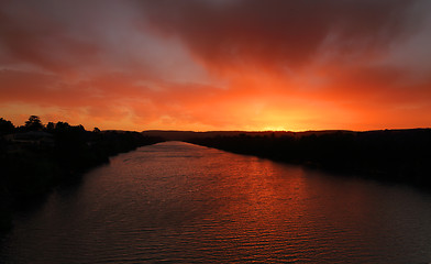 Image showing Red sky sunset over river with distant mountains 