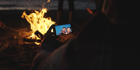 Image showing Couple taking photos beside campfire on beach