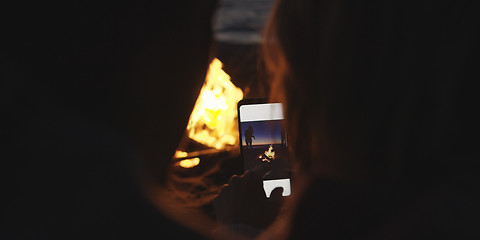 Image showing Couple taking photos beside campfire on beach