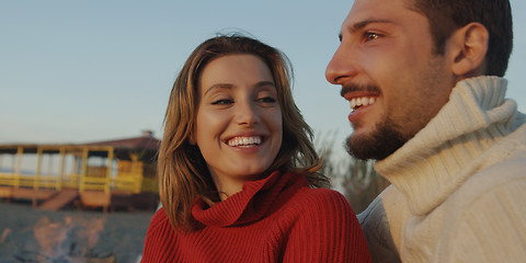 Image showing Loving Young Couple Sitting On The Beach beside Campfire drinkin