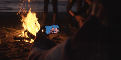 Image showing Couple taking photos beside campfire on beach