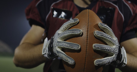 Image showing American football player holding ball while running on field