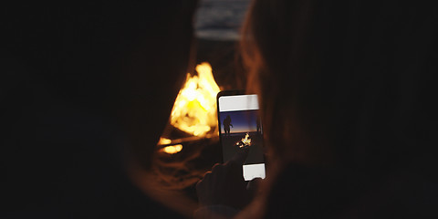 Image showing Couple taking photos beside campfire on beach