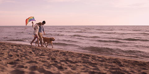 Image showing couple with dog having fun on beach on autmun day