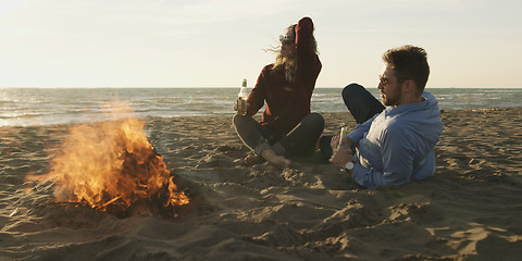 Image showing Loving Young Couple Sitting On The Beach beside Campfire drinkin