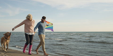 Image showing couple with dog having fun on beach on autmun day