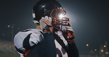 Image showing American Football Player Putting On Helmet on large stadium with